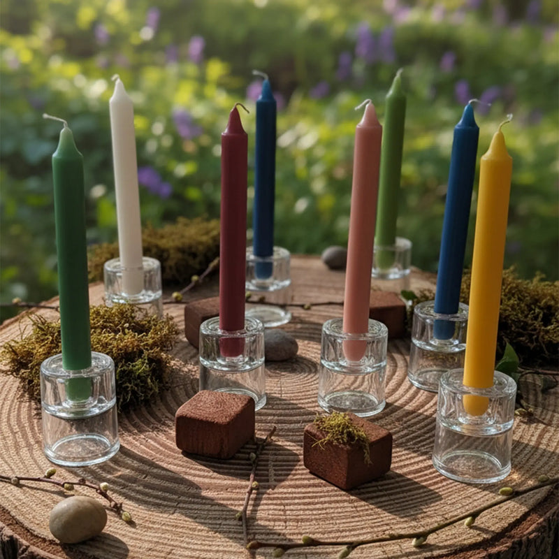 Collection de bougies bâtons teintées dans la masse de différentes couleurs, sur une souche d'arbre.