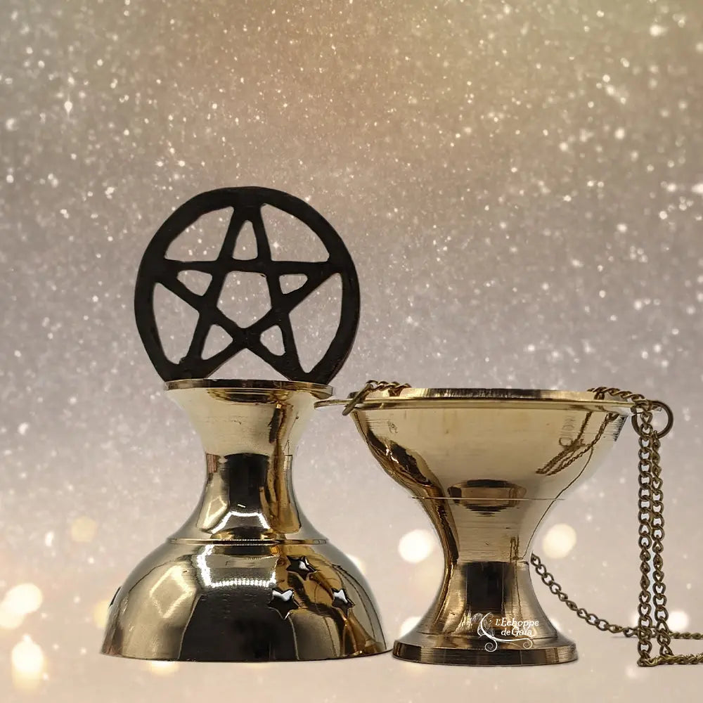 Encensoir/brûle-encens doré avec couvercle pentagramme noir et coupelle suspendue à une chaînette, sur fond lumineux pailleté.