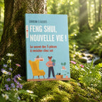 Livre bleu Feng Shui, nouvelle vie ! de Caroline Gleizes-Chevallier posé contre un arbre, illustré par une femme aménageant son salon avec des plantes et un fauteuil jaune.