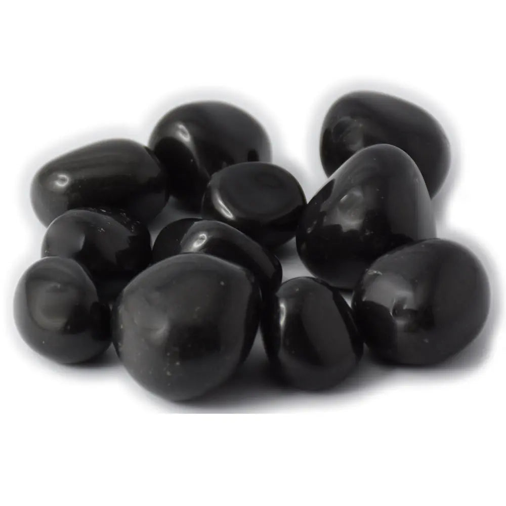 Un ensemble de pierres d'agate noire roulées aux surfaces lisses, sombres et uniformes, regroupées sur un fond blanc uni.