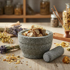 Résine d’ambre brute en morceaux dorés dans un mortier en pierre grise avec fleurs séchées et encens.