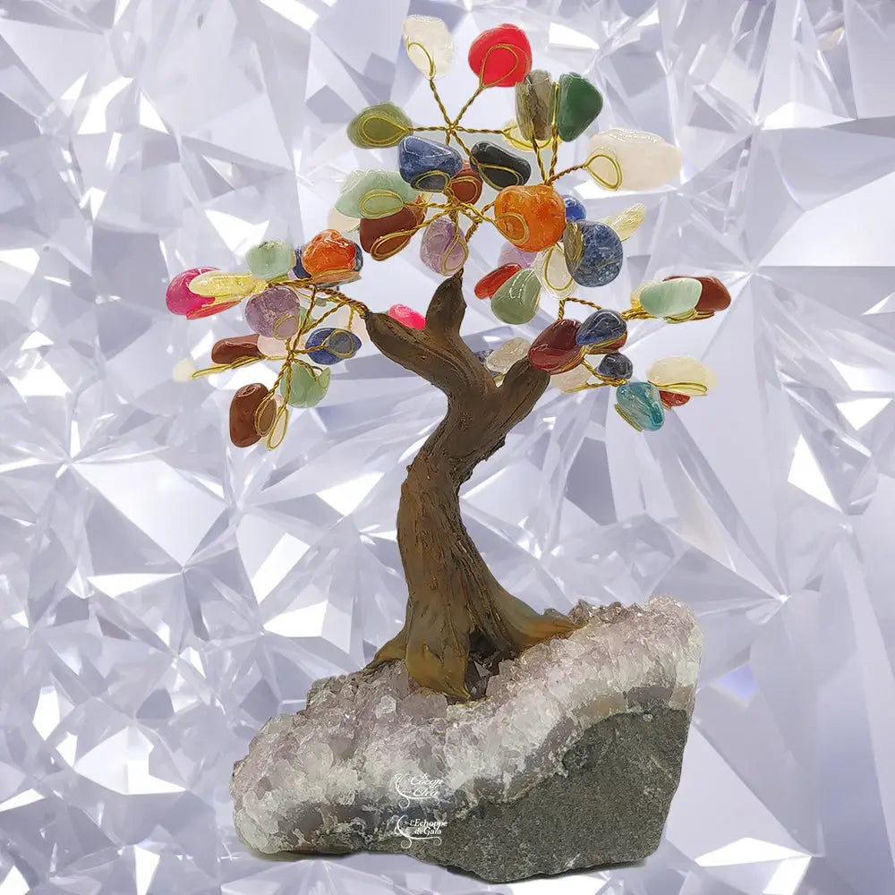 Arbre du bonheur avec un tronc torsadé et des feuilles en pierres naturelles multicolores, scellé sur un socle en bloc d'améthyste brute, devant un fond géométrique blanc.