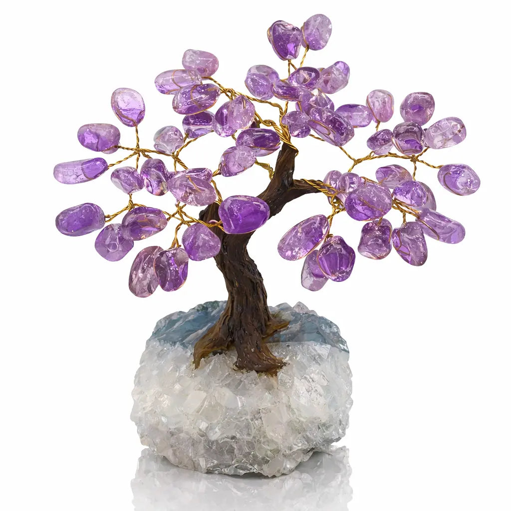 Un arbre du bonheur décoratif avec un tronc sombre texturé et des feuilles en améthyste violette montées sur fils dorés, reposant sur un socle massif de cristal de roche blanc.