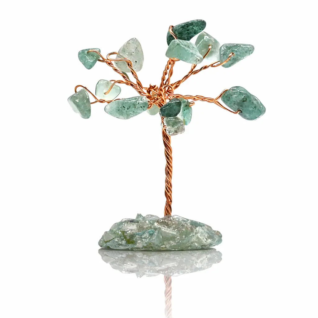 Un arbre du bonheur miniature composé d'un tronc en fils de cuivre torsadés et de feuilles en aventurine verte, reposant sur un socle de pierre brute sur un fond blanc avec reflet.
