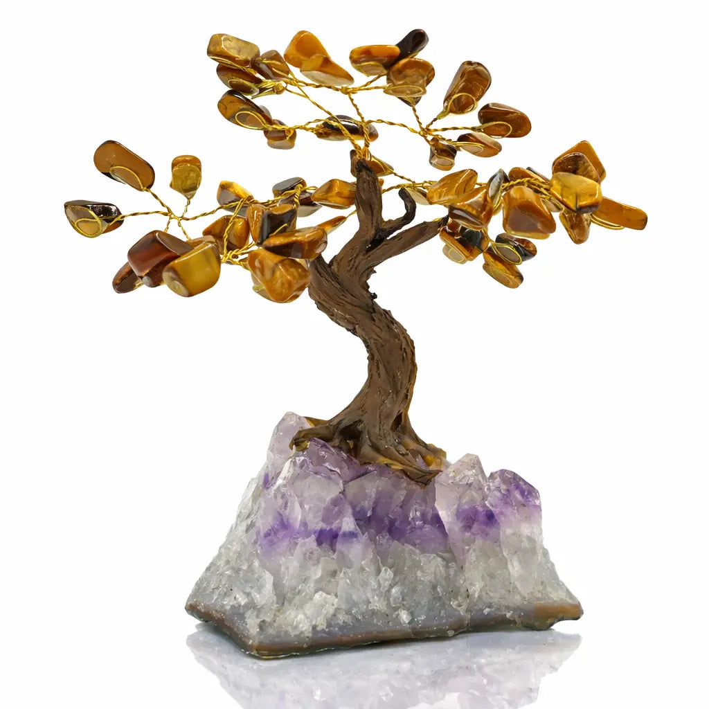 Un arbre du bonheur décoratif avec un tronc sculpté et des feuilles en pierres d'œil de tigre, s'élevant d'un socle en amas d'améthyste brute, présenté sur un fond blanc.