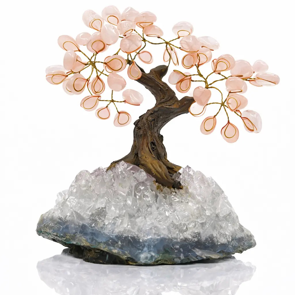 Un arbre du bonheur décoratif avec un tronc tortueux et des feuilles en quartz rose, s'élevant d'un imposant socle en cristal de quartz brut, présenté sur un fond blanc.