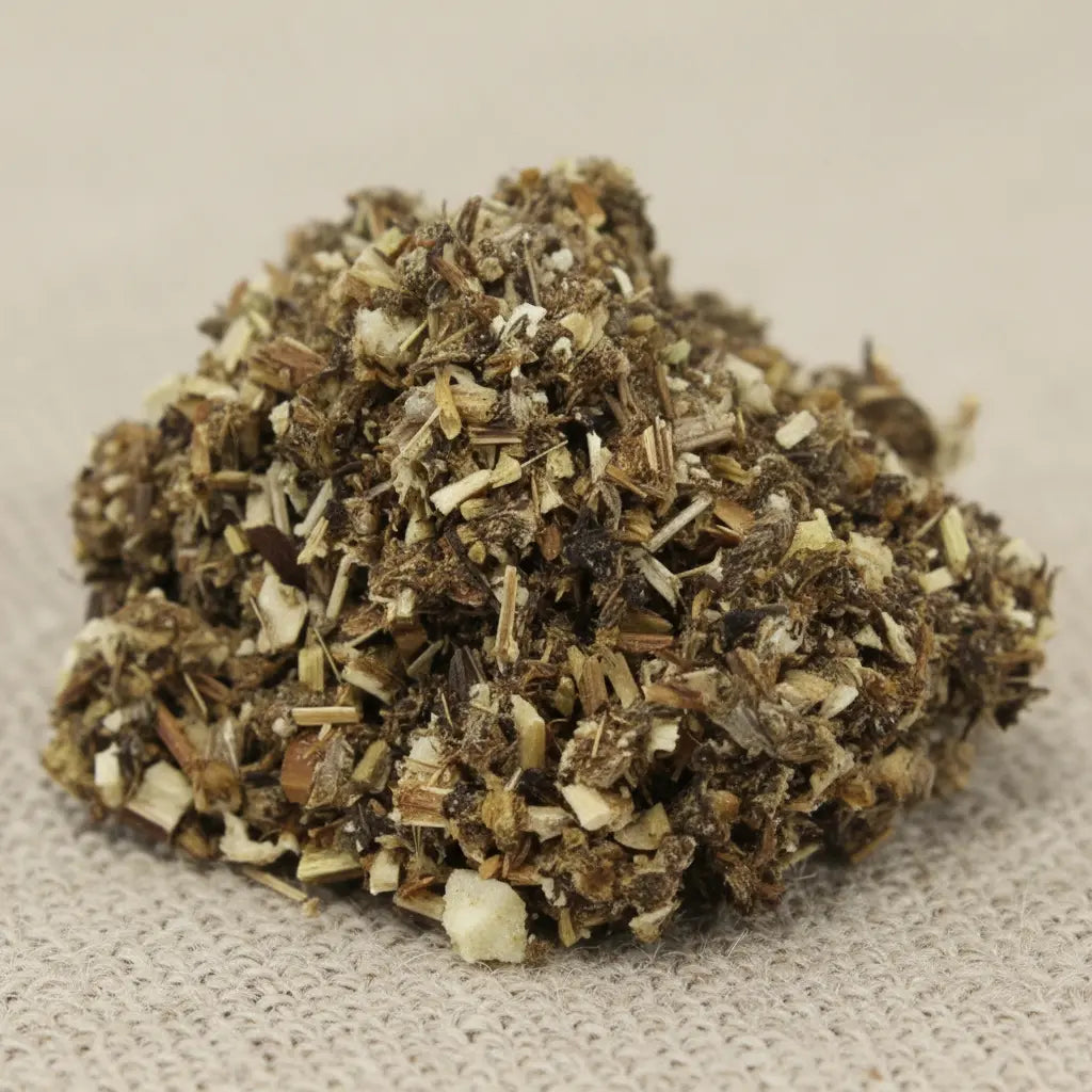 Armoise pour fumigation, mélange d’herbes sèches brun-vert finement coupées sur fond de tissu beige.