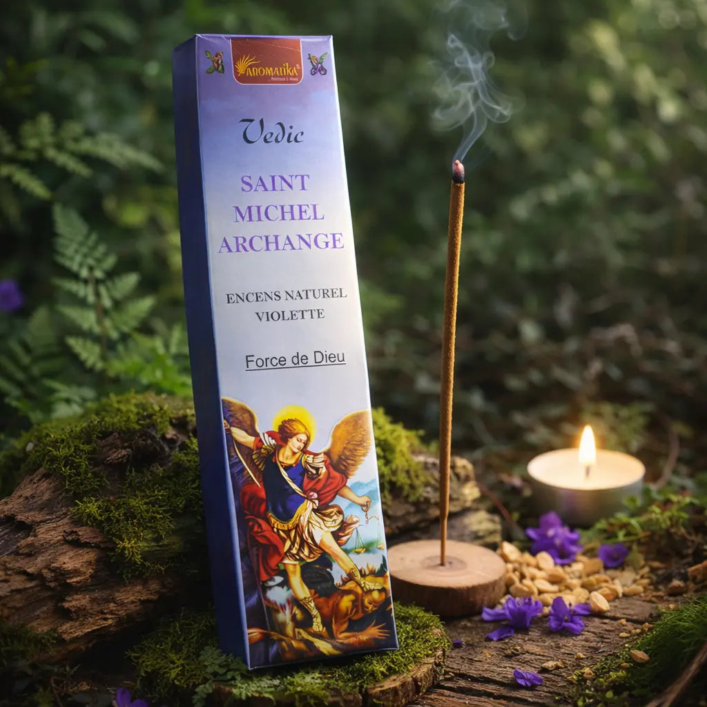 Boîte bleue d'encens Saint Michel Archange Aromatika illustrée du Prince de la Milice Céleste, posée sur une souche moussue en forêt avec un bâtonnet fumant, une bougie et des fleurs de violette.