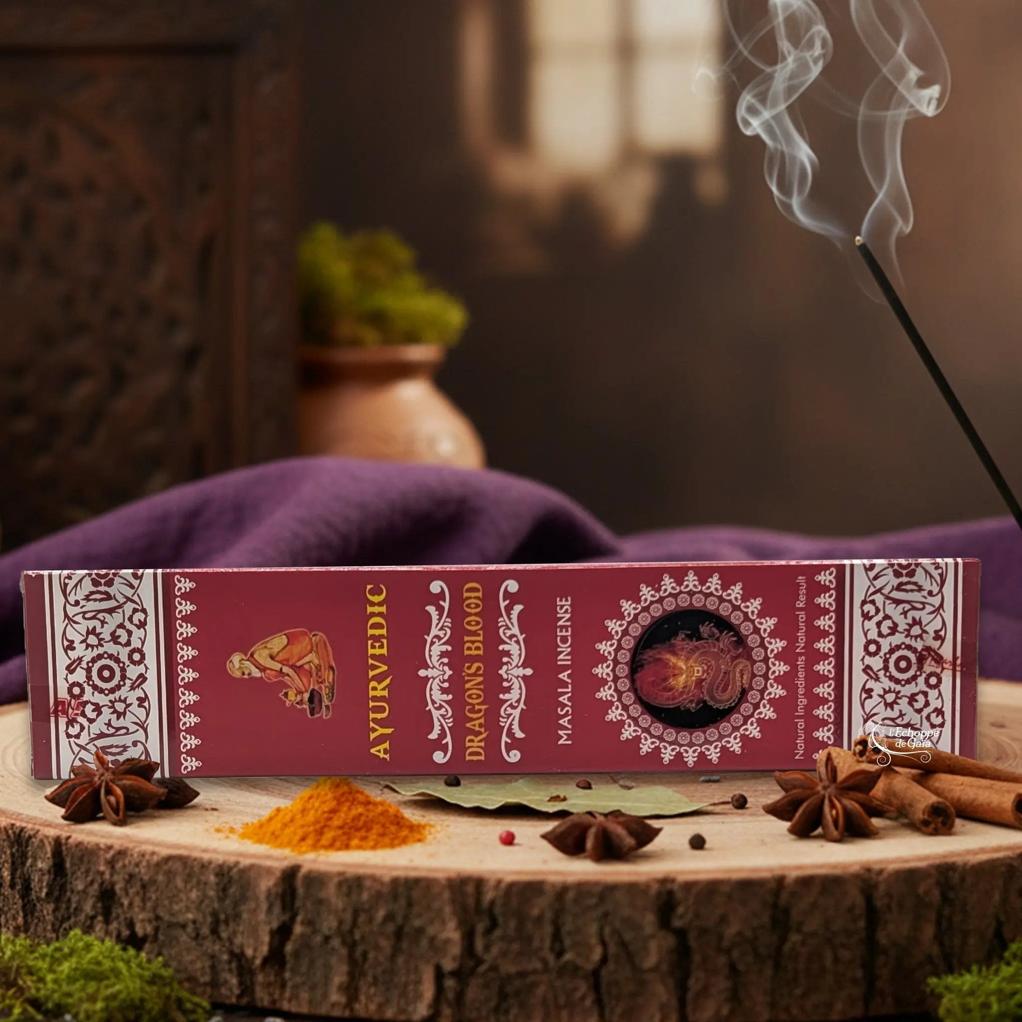 Boîte d'encens "Ayurvedic Dragons Blood Masala" sur une rondelle de bois, avec épices et encens fumant.