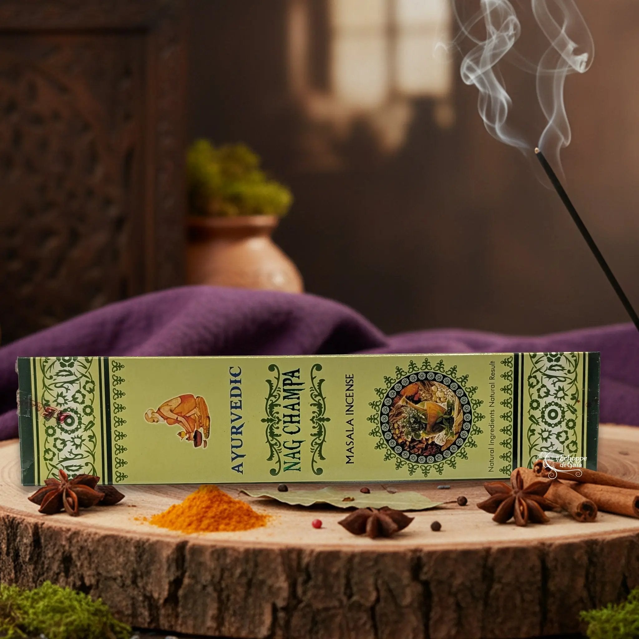 Boîte d'encens "Ayurvedic Nag Champa Masala" sur une rondelle de bois, avec épices et encens fumant.