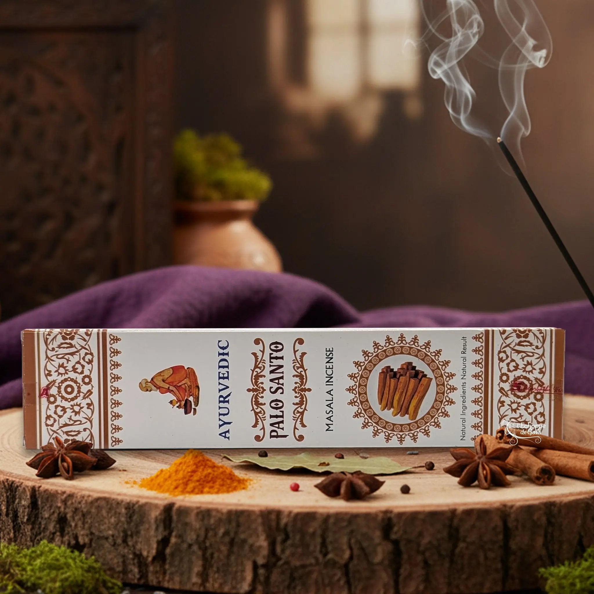Boîte d'encens "Ayurvedic Palo Santo Masala" sur une rondelle de bois, avec épices et encens fumant.