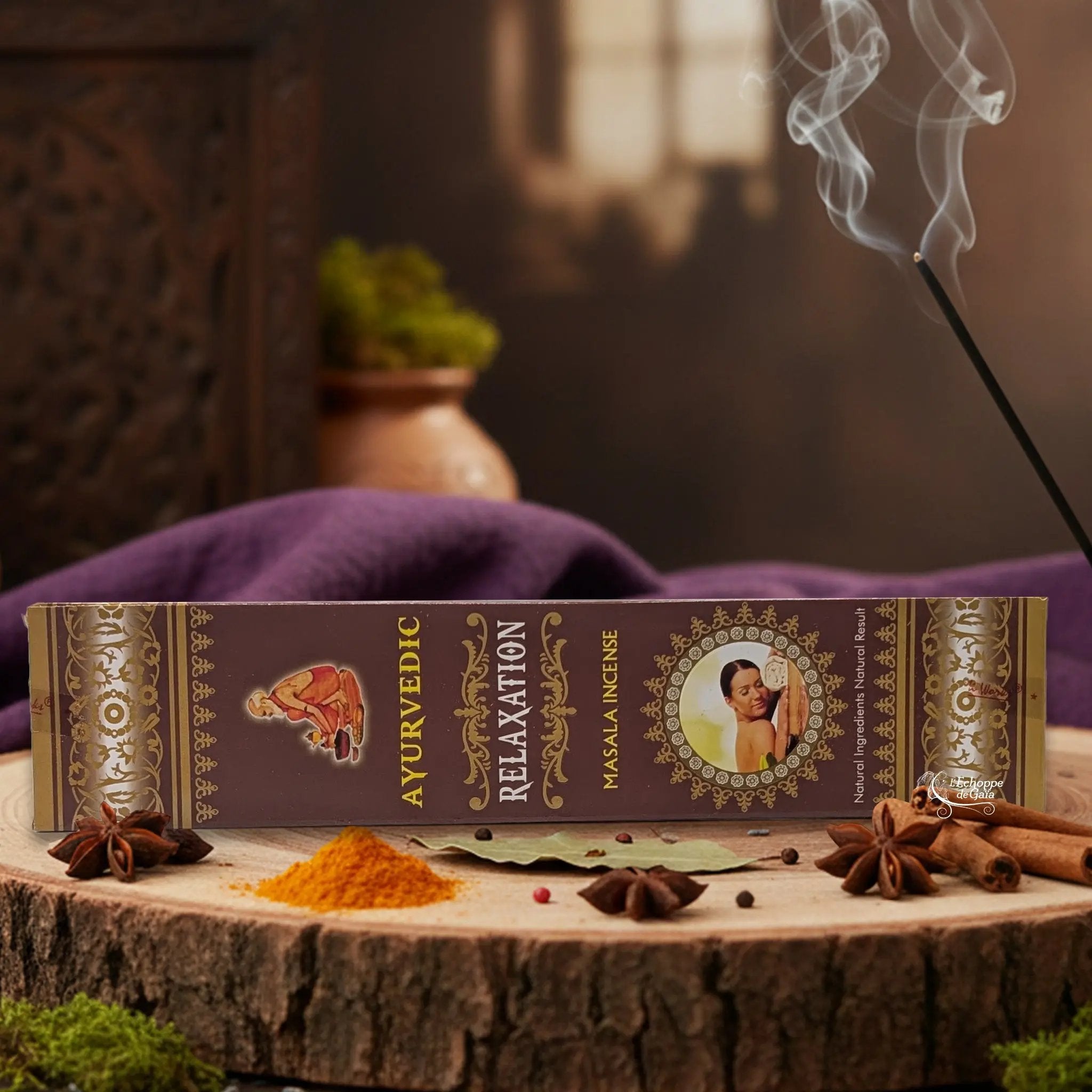 Boîte d'encens "Ayurvedic Relaxation Masala" sur une rondelle de bois, avec épices et encens fumant.