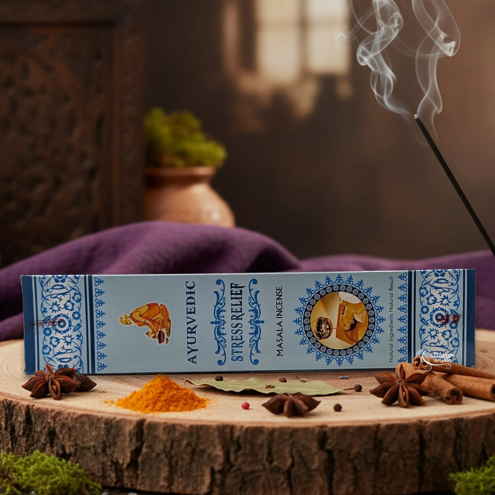 Boîte d'encens "Ayurvedic Stress Relief Masala" sur une rondelle de bois, avec épices et encens fumant.