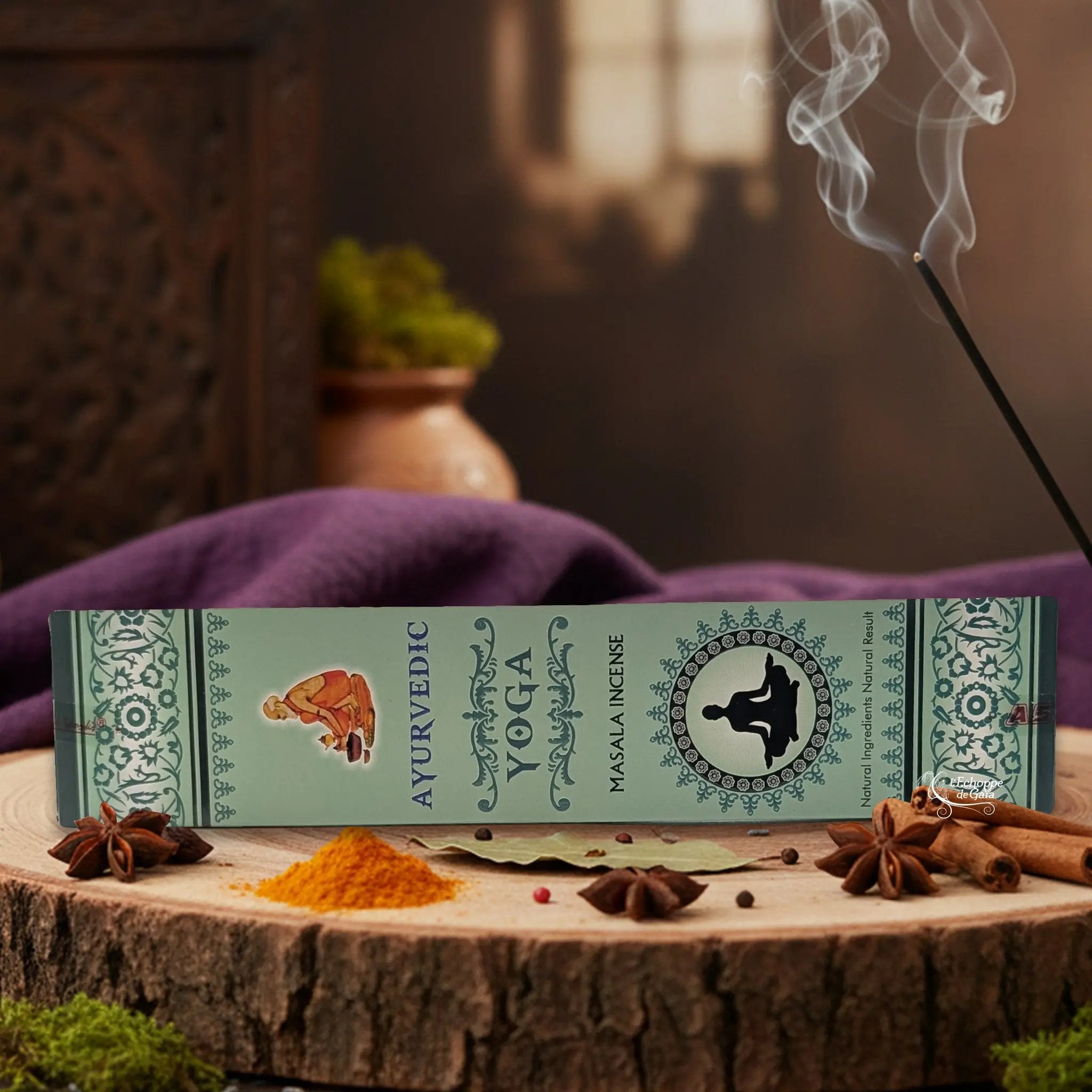 Boîte d'encens "Ayurvedic Yoga Masala" sur une rondelle de bois, avec épices et encens fumant.