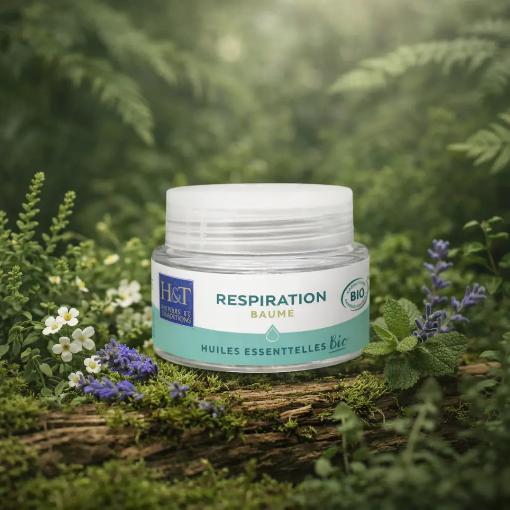 Pot en verre du Baume Respiration aux Huiles Essentielles Bio Herbes et Traditions posé sur une branche moussue entouré de fleurs blanches, lavande et menthe.