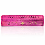Boîte porte-encens en bois rose fermée, arborant des incrustations dorées de lunes, d'étoiles et d'un soleil, avec un couvercle finement ajouré de motifs losanges, sur fond blanc.