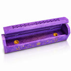 Boîte porte-encens en bois violet entrouverte, décorée de lunes, d'étoiles et d'un soleil dorés, révélant deux petites coupelles en laiton à l'intérieur, sur fond blanc.