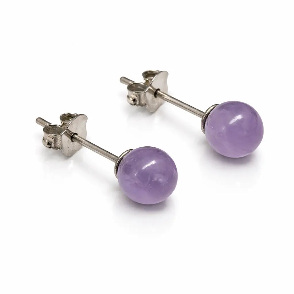 Une paire de boucles d'oreilles puces en argent, ornées de perles rondes en améthyste d'un violet tendre aux reflets naturels, présentées sur un fond blanc avec reflet.
