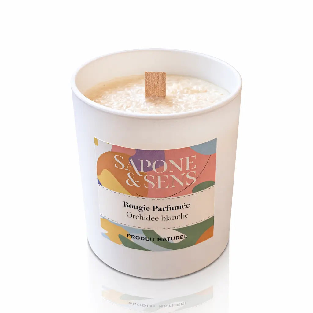 Une bougie parfumée naturelle « Orchidée blanche » de la marque Sapone & Sens, présentée dans un pot en céramique blanche avec une mèche en bois, sur un fond blanc.