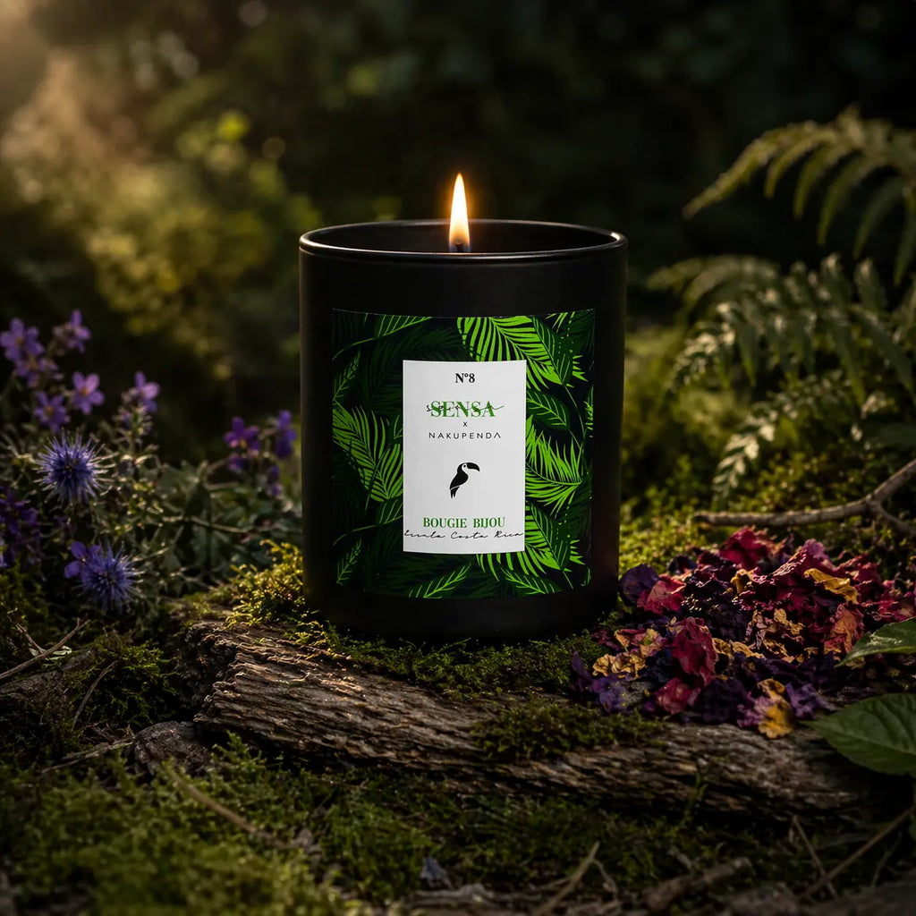 Bougie bijou Sensa x Nakupenda n°8 allumée dans une forêt avec mousse, fougères et fleurs séchées.