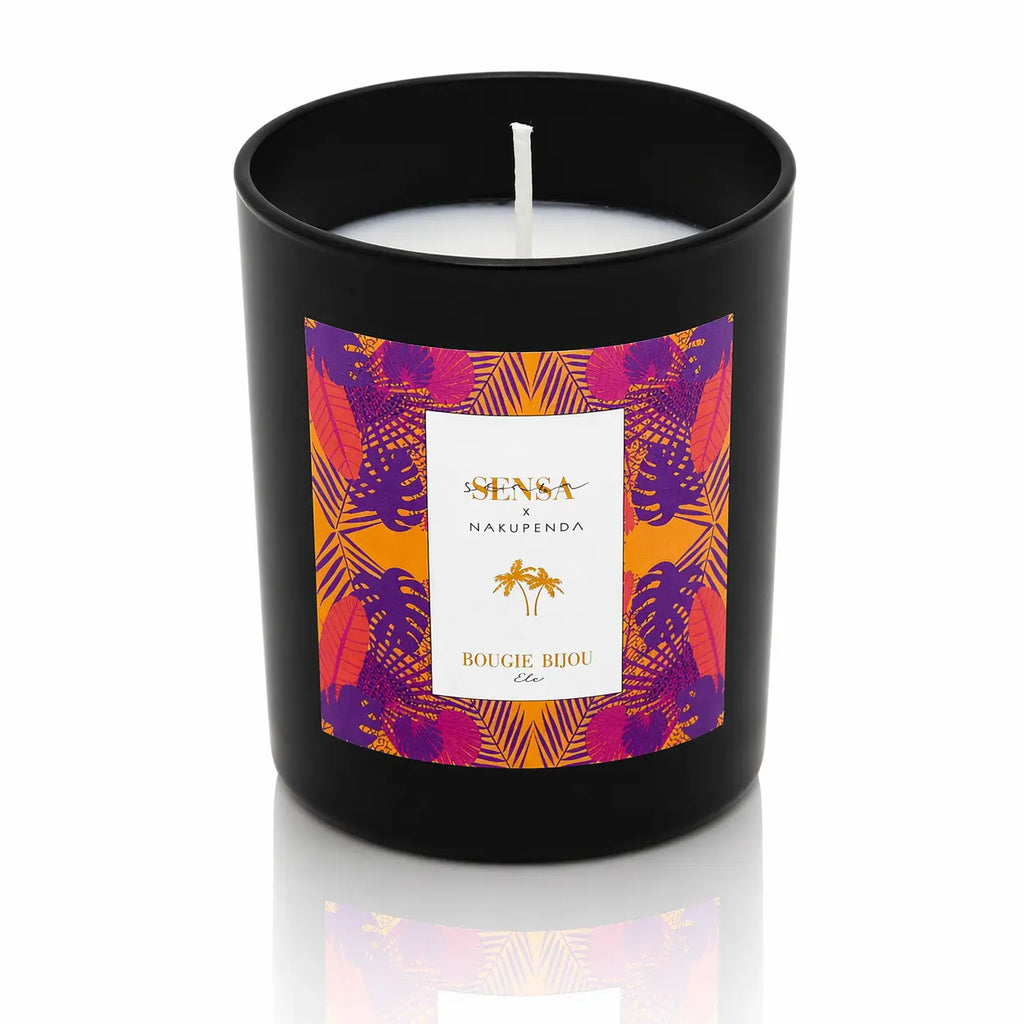 Bougie bijou Sensa x Nakupenda "Été" dans un pot noir mat avec étiquette tropicale orange et violette.
