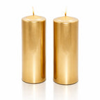 Un lot de deux bougies piliers métallisées dorées, de forme cylindrique, présentées debout sur un fond blanc avec un léger reflet à leur base.
