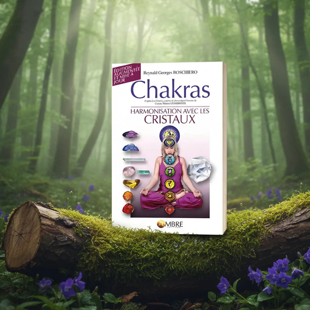Livre Chakras - Harmonisation avec les Cristaux de Reynald Georges Boschiero posé sur une souche moussue, illustré d'une femme en méditation avec les sept chakras alignés et des pierres de couleurs.