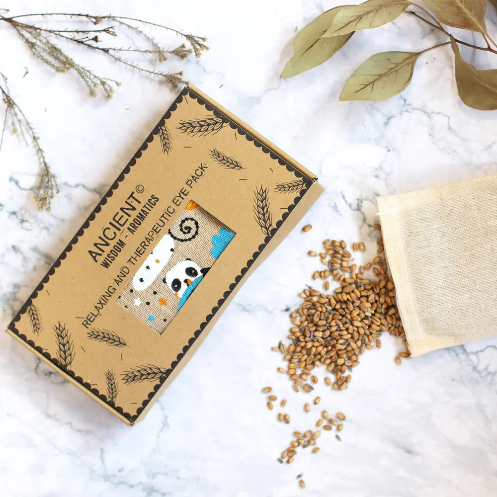 Masque de détente yeux panda dans sa boîte avec grains de blé et lavande sur fond marbre.