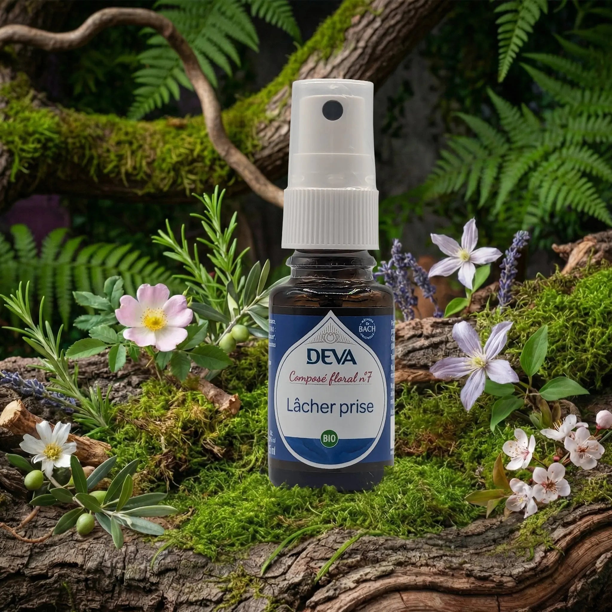 Flacon spray bleu du composé floral Deva Lâcher Prise N°7 posé sur une souche de bois moussue, entouré de fleurs sauvages et de feuillage vert.