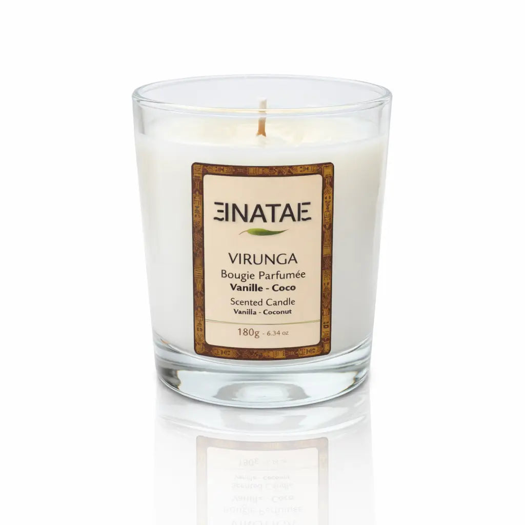 Une bougie parfumée naturelle « Virunga » (Vanille - Coco) de la marque Enatae, présentée dans un verre transparent simple, sur un fond blanc avec un reflet à sa base.
