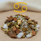 Gros plan sur un encens astrologique Cancer, mélange de sels minéraux, copeaux de bois et petites fleurs séchées sur fond en bois clair.