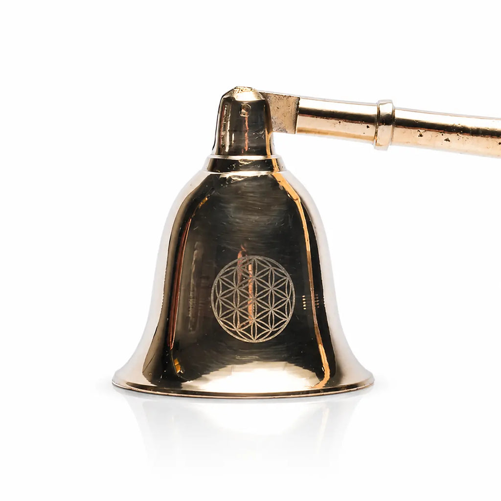 Gros plan sur la cloche d'un éteignoir à bougie dorée avec gravure du symbole Fleur de Vie.