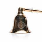 Gros plan sur la cloche d'un éteignoir à bougie dorée avec gravure du symbole Fleur de Vie.