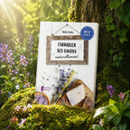 Livre Fabriquer ses Savons Naturellement de Kelly Cable posé contre un arbre, illustré de lavande, de sels violets et d'un pain de savon artisanal.