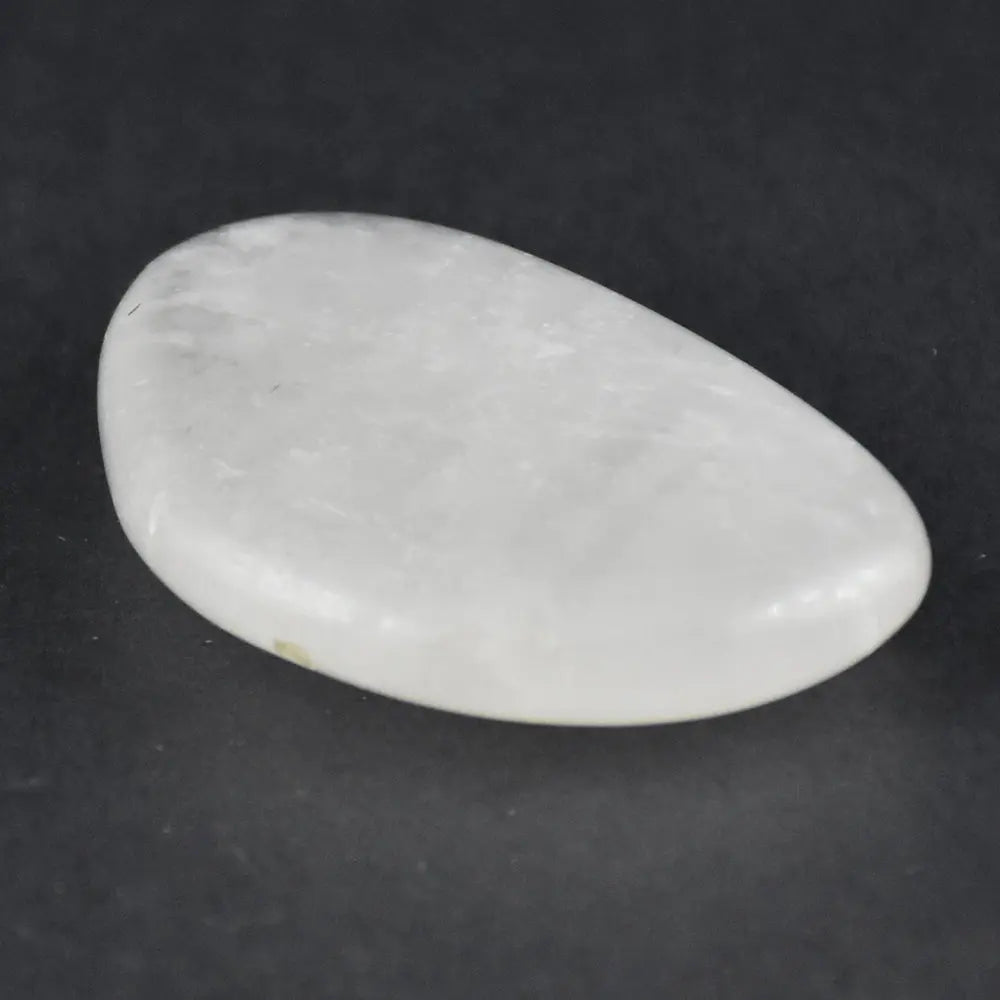 Un galet cristal de roche poli de forme ovale, blanc laiteux, présenté seul sur un fond noir.