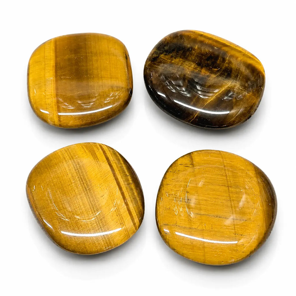 Ce lot de quatre galets polis en oeil de tigre dévoile des nuances dorées et brunes ainsi que des reflets chatoyants sur leur surface lisse.