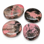 Galet de rhodonite poli et arrondi, mêlant des zones rose doux et des inclusions noires, isolé sur fond blanc.
