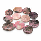 Galet poli de rhodonite aux nuances contrastées de rose et de noir, isolé sur un fond blanc avec un léger reflet à sa base.