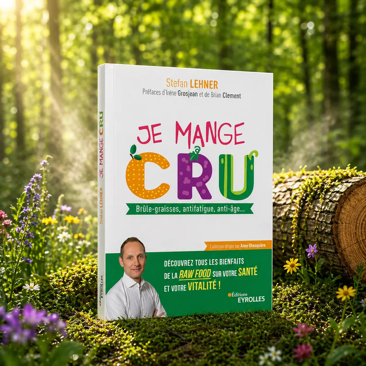 Livre blanc Je Mange Cru de Stefan Lehner posé dans la mousse forestière, montrant un titre illustré de fruits et légumes et le portrait de l'auteur.