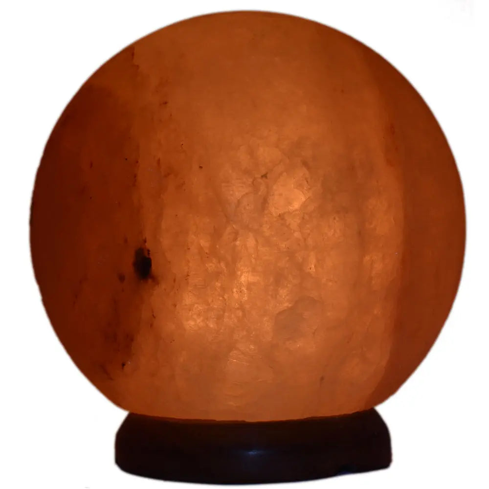 Lampe de sel rose de l'Himalaya sphérique allumée sur un socle en bois sombre