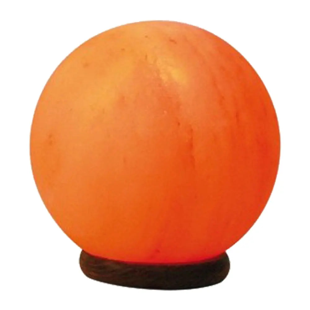 Lampe de sel rose de l'Himalaya taillée en sphère allumée sur un socle en bois rond