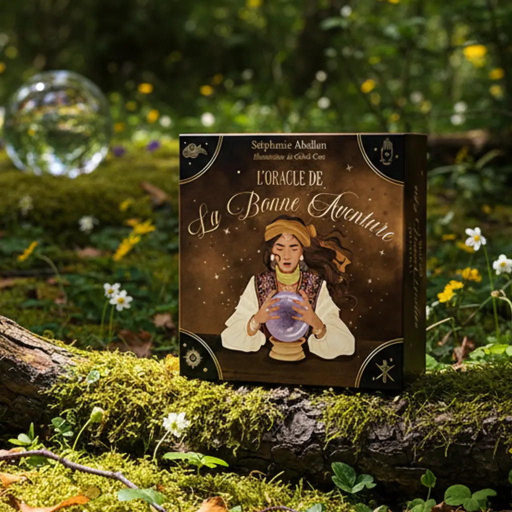 Coffret L'Oracle de La Bonne Aventure de Stéphanie Abellan posé sur une souche moussue en forêt, ambiance mystique avec boule de cristal en arrière-plan.