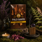 Carnet marron de Papier d'Encens Fragrances & Sens - Palo Santo illustré de morceaux de bois sacré, posé près d'une lamelle allumée en accordéon exhalant de la fumée.