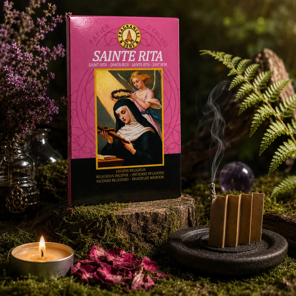 Carnet rose de Papier d'Encens Fragrances & Sens - Sainte Rita illustré de la sainte recevant une couronne d'épines par un ange, posé près d'une lamelle allumée en accordéon exhalant de la fumée.