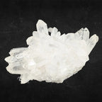 Amas de cristal de roche brut à pointes multiples translucides sur un fond noir.