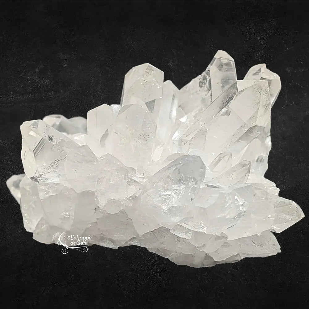 Amas de cristal de roche brut aux pointes naturelles translucides sur fond noir.
