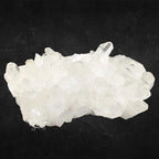 Large amas de quartz cristal de roche blanc et translucide montrant de nombreuses pointes naturelles sur fond noir.