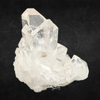 Amas de cristal de roche blanc présentant des pointes prismatiques inclinées sur un fond noir sombre.
