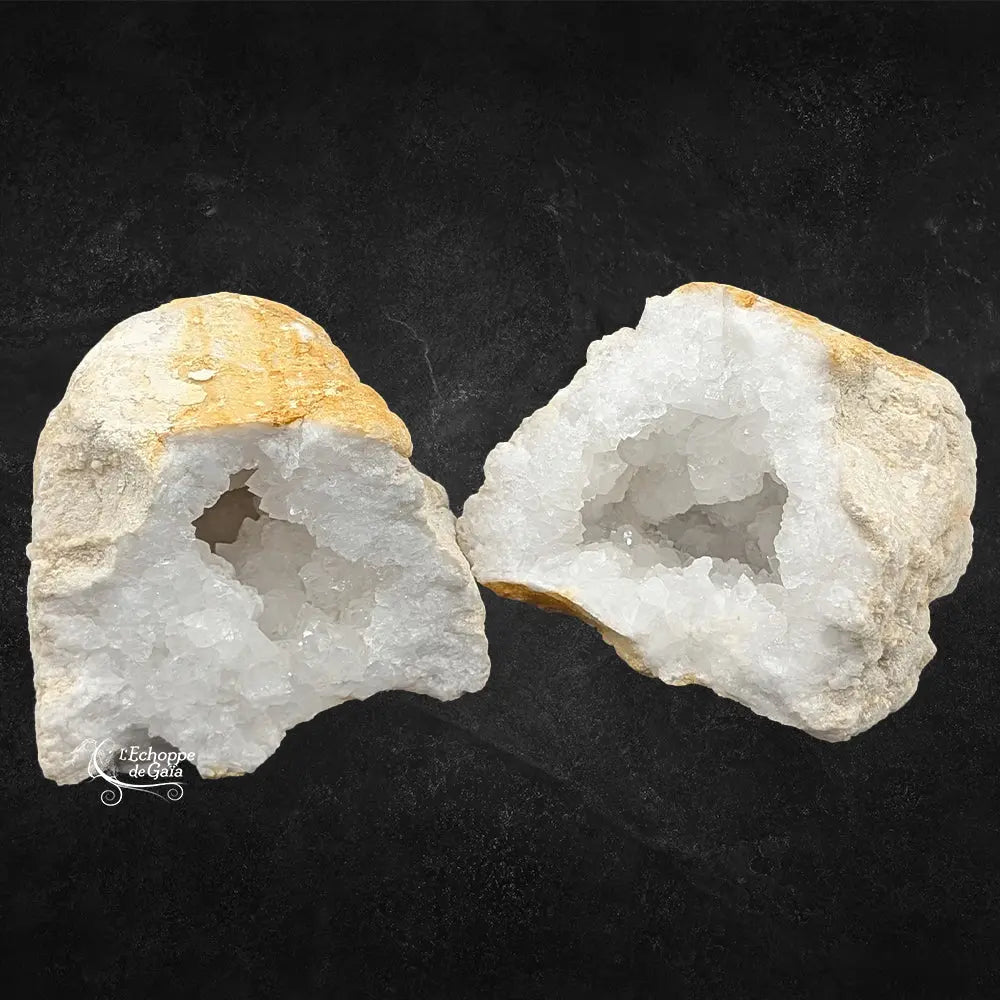 Géode de quartz blanc ouverte montrant une croûte ocre et des cristaux internes brillants sur fond noir.