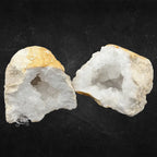 Géode de quartz blanc ouverte montrant une croûte ocre et des cristaux internes brillants sur fond noir.